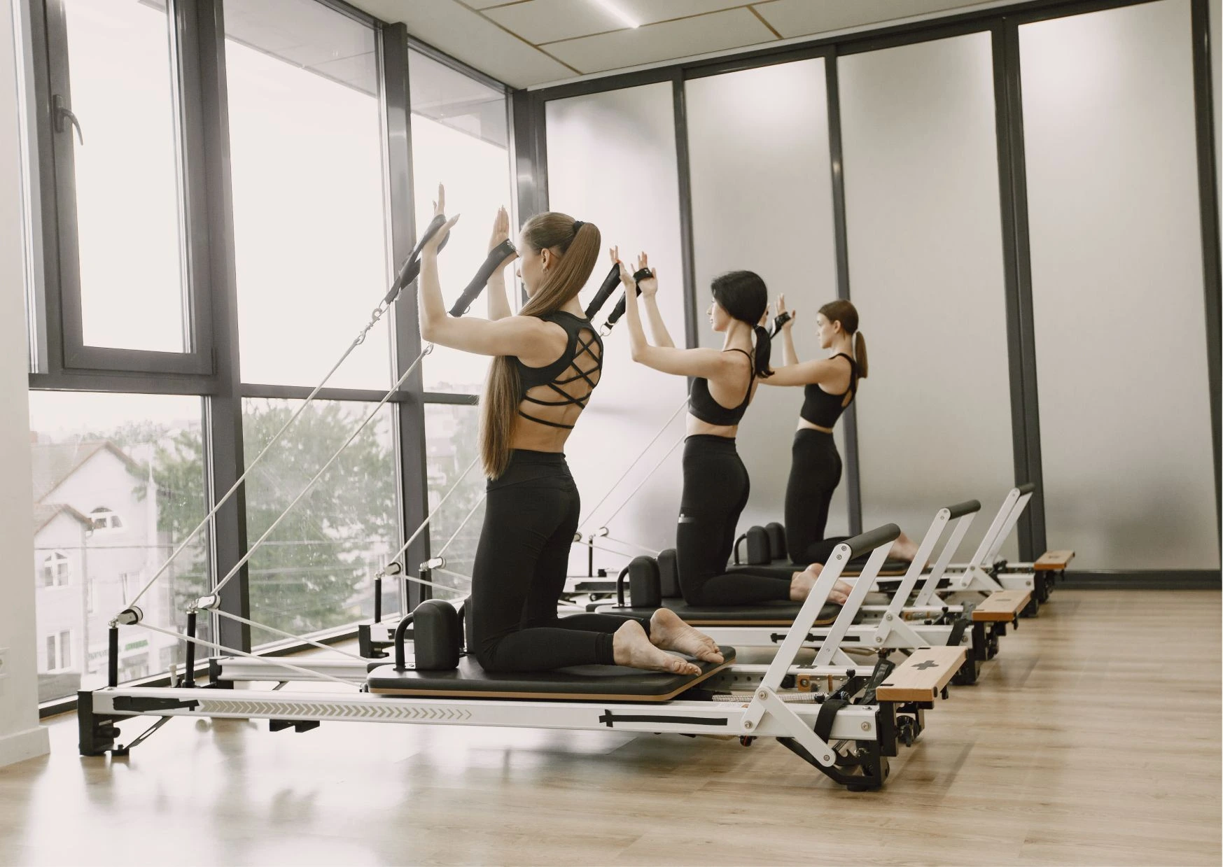 Frauen trainieren im Pilates-Studio mit Reformer-Geräten zur Kräftigung der Schultern und Arme