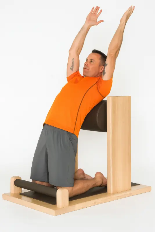Mann macht Rückbeuge auf Knien an gepolstertem Trainingsmodul aus Holz