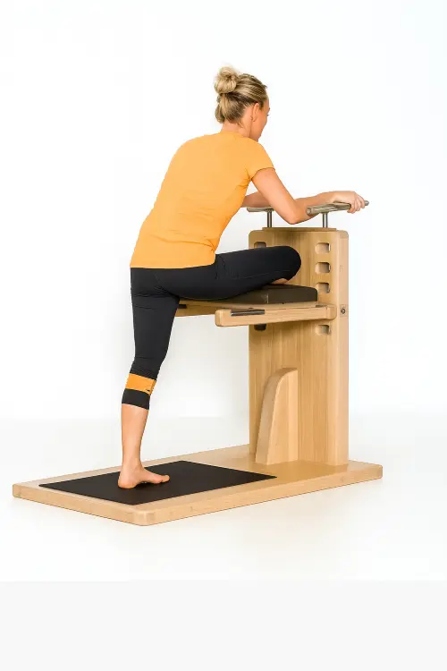 „Frau dehnt Oberschenkel an hölzernem Trainingsgerät im Stehen