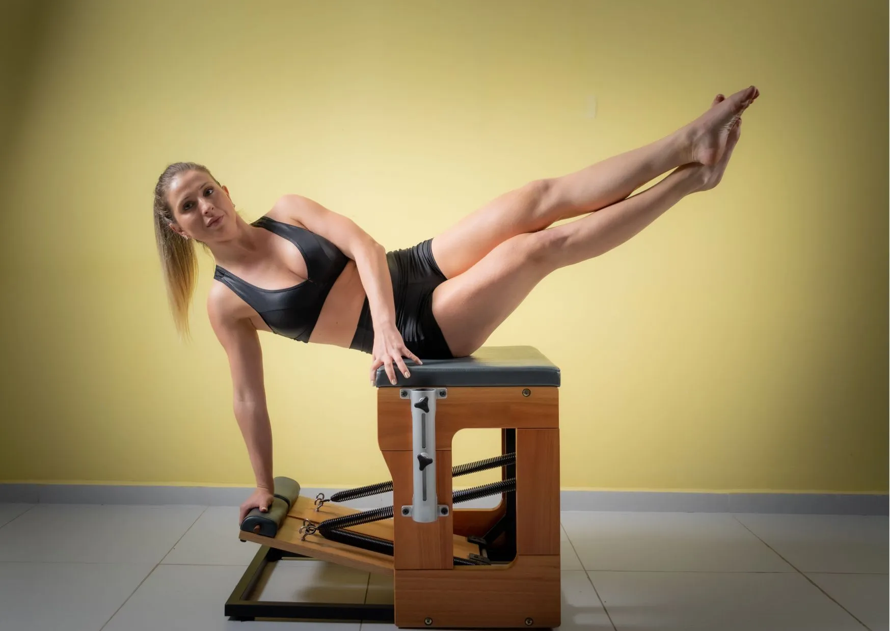 Frau führt seitliche Beinübung auf Wunda-Chair zur Stärkung der Körpermitte durch