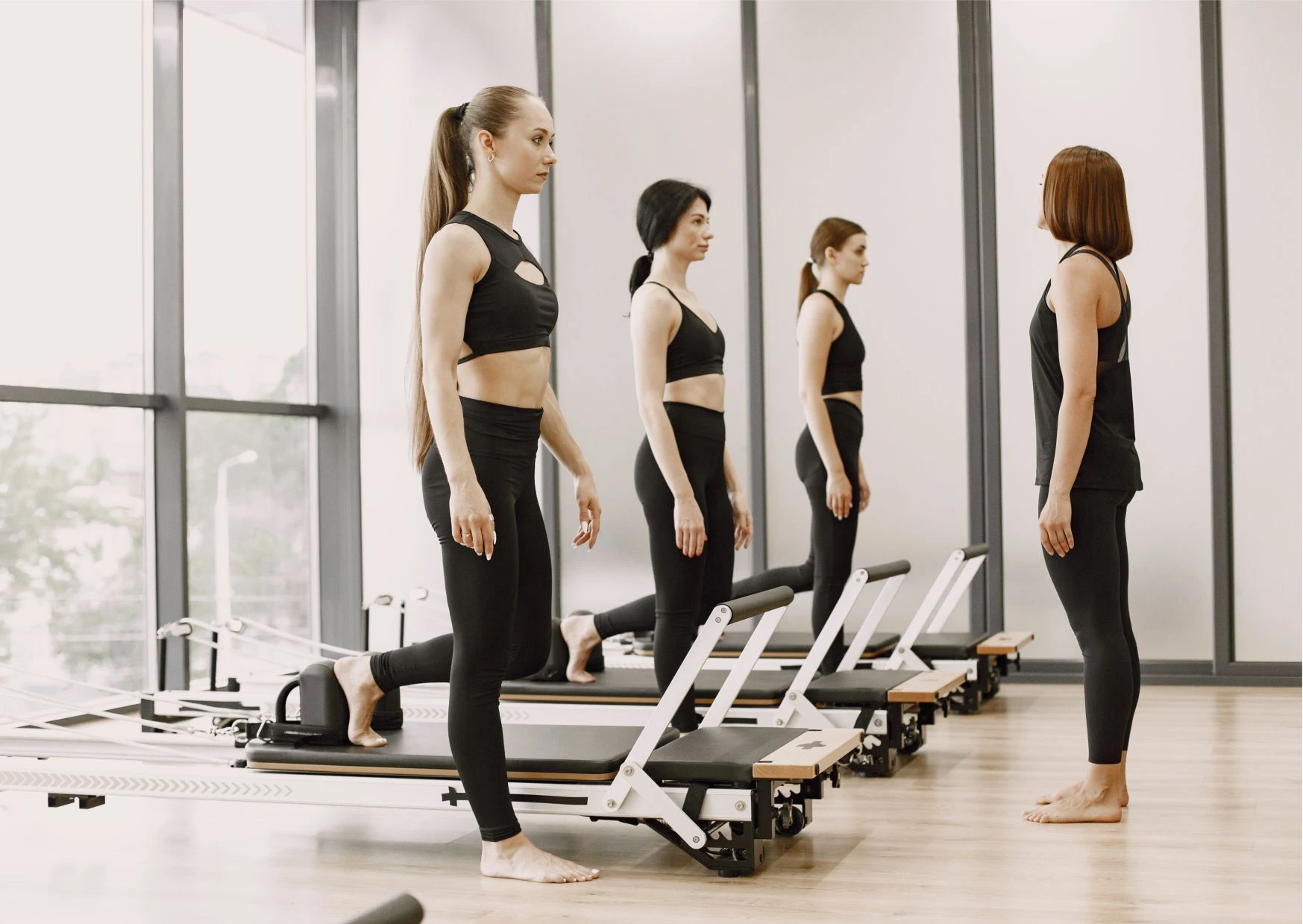 Pilatestrainerin gibt Anleitung für Reformer-Übungen an eine Frauengruppe im Studio